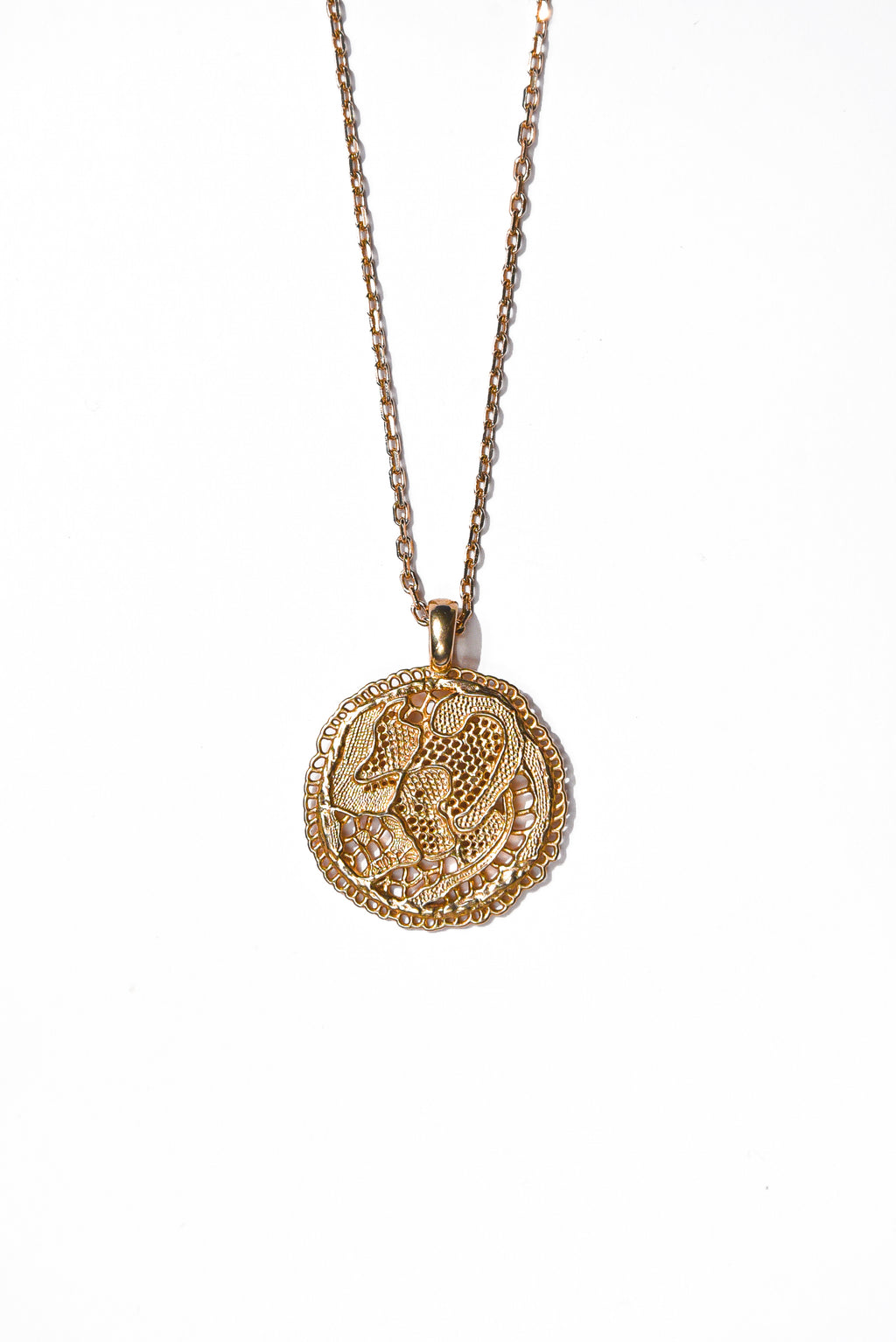 Collier Grâce Maison Elise D. en vermeil doré à l'or 18 carats, avec pendentif médaille ronde ajourée façon dentelle, sur fond blanc. 