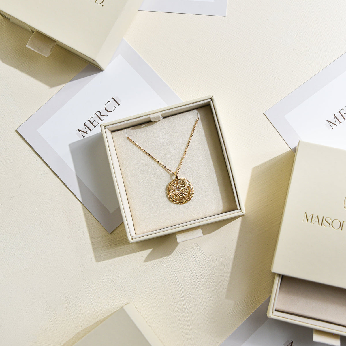 Collier Grâce en vermeil doré à l'or 18 carats, avec médaille entelle ajourée, présenté dans son écrin beige Maison Elise D., accompagné d'une carte de remerciement.