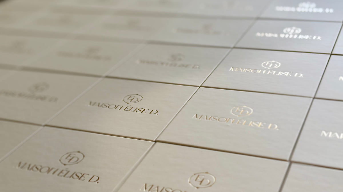 Gros plan en perspective sur les écrins de bijoux Maison ELise D., aux finitions élégantes et au logo doré sur fond beige. 